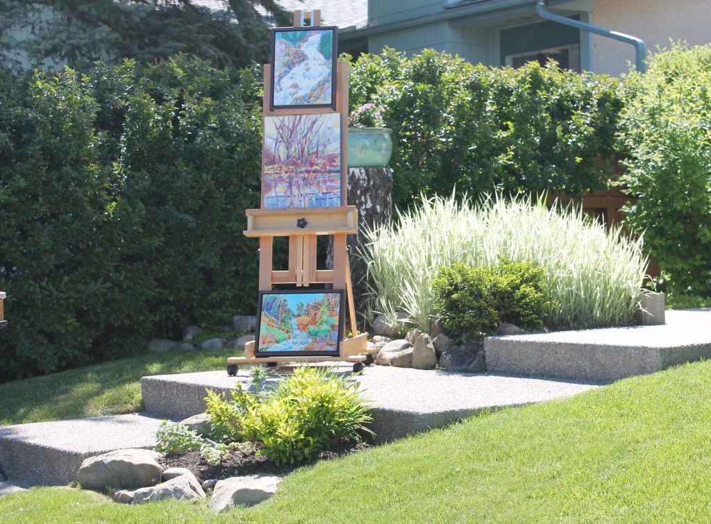 An ‘art in the garden’ display of framed paintings in an ornamental garden 