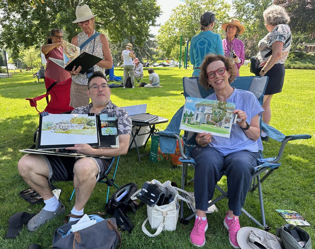 Watercolour painters Marc Taro Holmes and Shari Blaukopf, seated in their chairs, showing their paintings