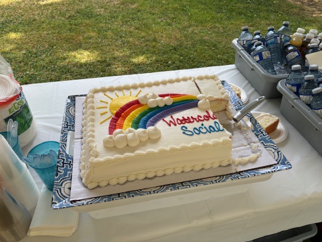Photograph of a sheet cake decorated with a rainbow and the words watercolor social in icing 