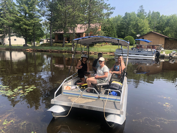 People in a pontoon boat on the water on the Goulais River