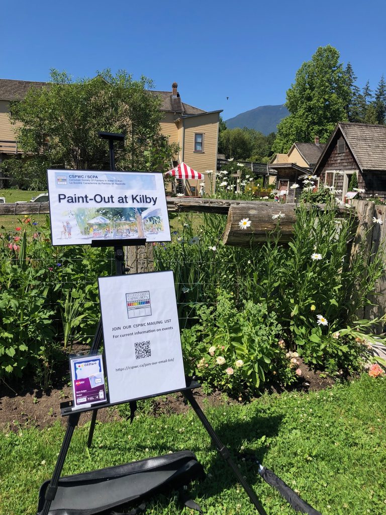 Welcome sign for a paint out at Kilby Historic Village. Buildings of the village visible in the background